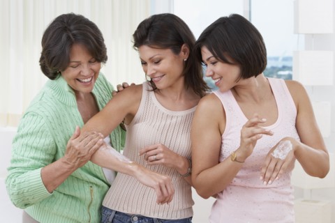 Mother and sisters applying lotion to skin