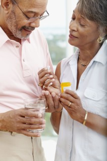 African woman helping husband take medication