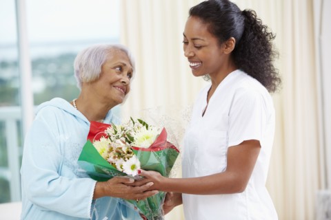 African American woman giving nurse bouquet of flowers