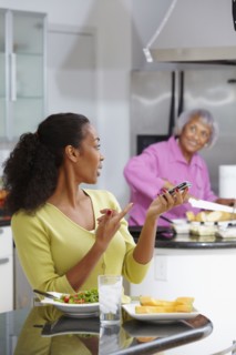African American woman eating salad and talking on cell phone
