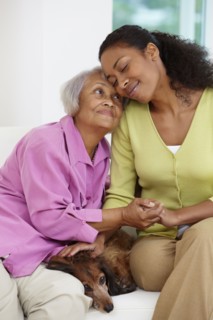 African American woman sitting on sofa with mother and dog