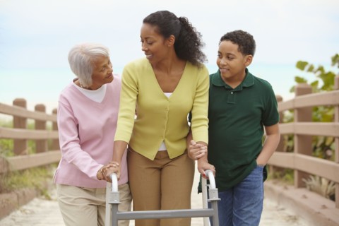African American woman using walker with help of family