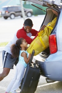 African American father and daughter loading car