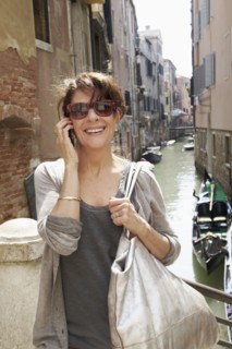 Smiling Italian woman talking on cell phone near canal