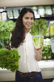Hispanic woman holding lettuce in grocery store