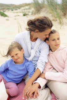 Caucasian mother and daughters hugging on beach