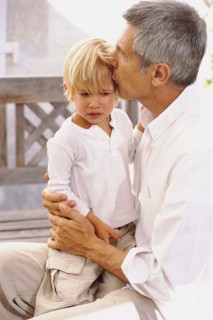 Caucasian father kissing crying son outdoors