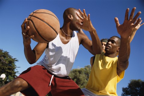 Men playing basketball outdoors