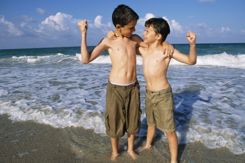 Boys flexing their muscles on beach