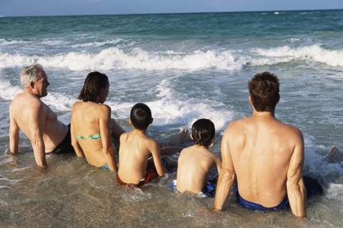 Family sitting in waves on beach
