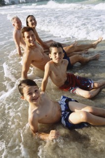 Family sitting in waves on beach