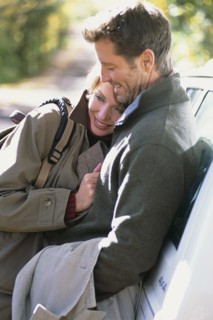 Couple hugging by car