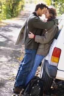 Couple hugging by car