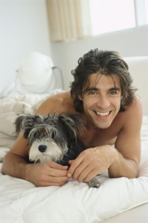 Man hugging dog on bed