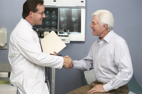 Doctor shaking patient's hand in hospital room