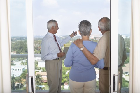 Realtor showing senior couple view from balcony