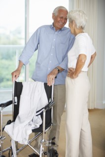 Senior couple standing by wheelchair