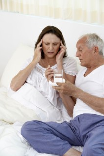 Senior man giving wife painkillers in bed