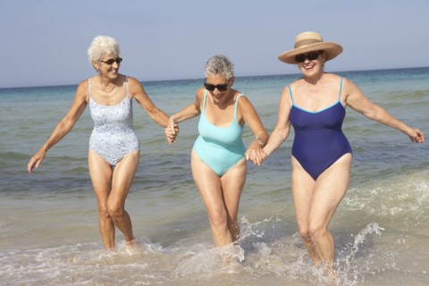 Senior women walking in waves on beach