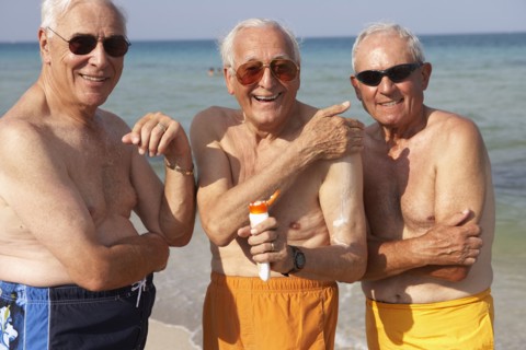 Senior men applying sunscreen on beach