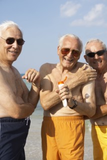 Senior men applying sunscreen on beach