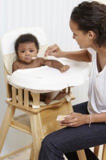 Mother feeding baby in high chair