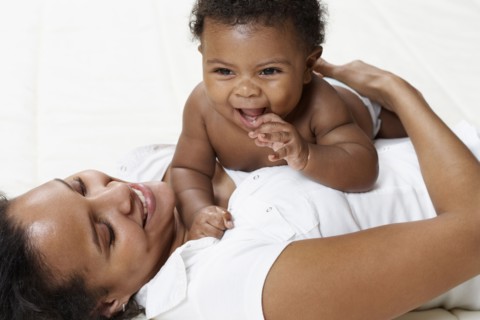 Mother and baby playing on bed