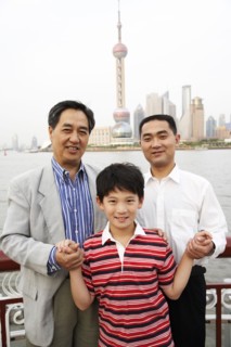 Three generations of men smiling by city skyline