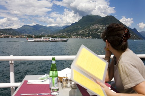 Woman reading menu in restaurant overlooking rural lake