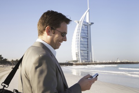 Caucasian businessman using cell phone on beach