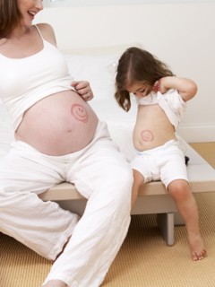 Caucasian girl and pregnant mother with drawings on bellies