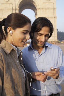 Indian couple listening to headphones by monument
