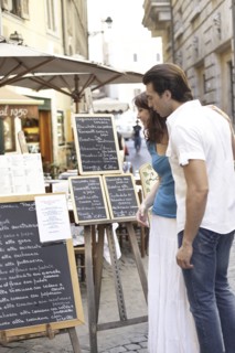 Caucasian couple reading menus on city street
