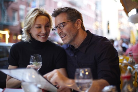 Caucasian couple reading menu at urban cafe
