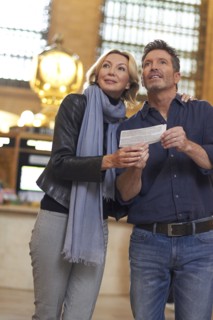 Caucasian couple reading train schedule in Grand Central Station