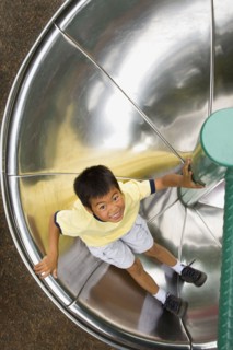 Asian boy sliding down circular slide