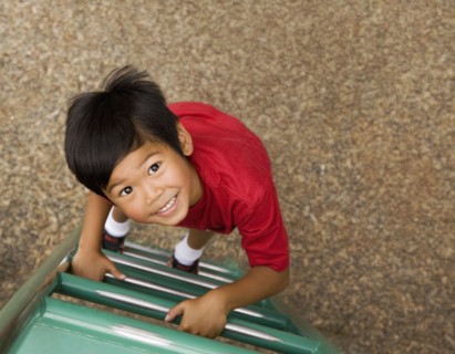 Asian boy climbing ladder on playground