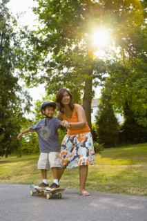 Asian mother helping son learn to skateboard