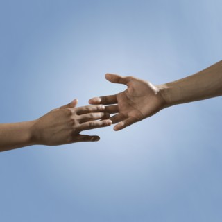 Mixed race people reaching out hands toward one another