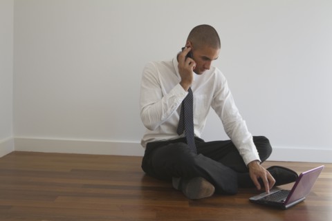 Mixed race businessman using laptop on floor