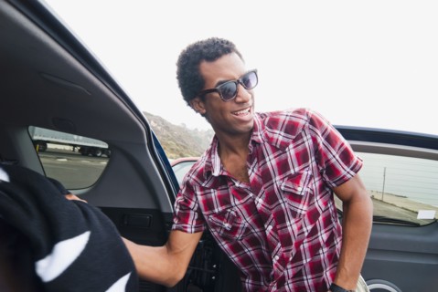 Mixed race man removing blanket from back of car