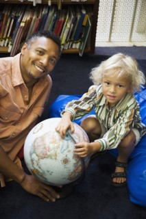 Father and son with globe in library