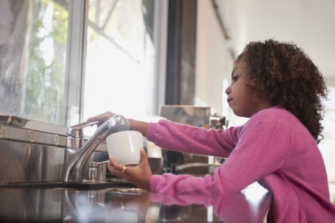 Mixed race girl washing dishes