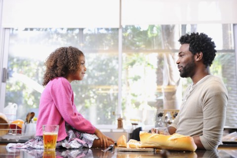 Father and daughter eating in kitchen