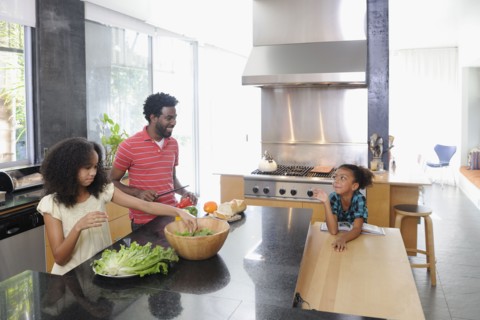 Father and daughters preparing food in kitchen