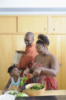 Black family preparing salad in kitchen