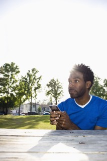 African American man text messaging outdoors