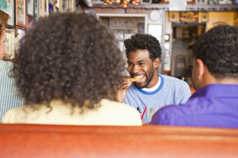 Smiling friends eating in diner booth