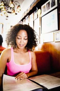 Smiling African American woman reading menu in diner