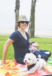 Mother and newborn baby sitting with dog in park
